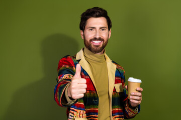 Poster - Photo of satisfied handsome man wear trendy clothes drink coffee thumb up isolated on khaki color background