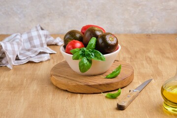 Wall Mural - Different varieties of tomatoes in a ceramic bowl on a wooden background. Ingredients for salads.