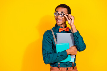 Wall Mural - Photo portrait of handsome young guy look empty space hold copybooks dressed stylish suit garment isolated on yellow color background