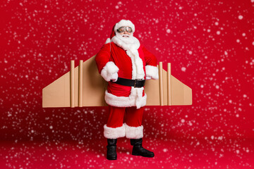 Poster - Full length photo of retired grandpa white beard jetpack hands hips self-assured prepare round-the-world fly trip wear santa x-mas costume coat spectacles cap isolated red color background