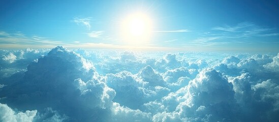 Wall Mural - A view from above the clouds with a bright blue sky and a sun shining.