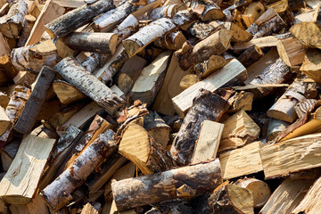 Stack of birch firewood with hand chopping block. Chopped firewood for winter. Lot of firewood - harvesting wood for heating the house. Horizontal photo. Chopped firewood background and texture.