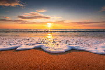 Beautiful cloudscape over the sea and beach, waves on the sand.