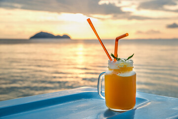 Fresh fruit cocktails on tropical island with sunset light sea view background.