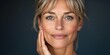 © Sasint - Elegant middle-aged woman softly touching her neck, emphasizing the smooth texture of her skin, with a calm and confident look in a softly lit setting
