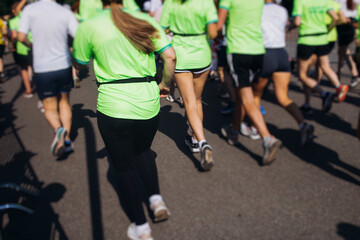 Wall Mural - Marathon runners crowd, sportsmen participants start running the half-marathon in the city streets, crowd of sportswomen joggers in motion, group athletes outdoor training competition in a summer day