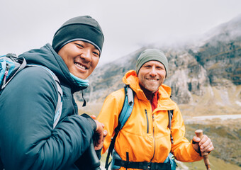Wall Mural - caucasian and sherpa men with backpacks together smiling at camera makalu barun park trekking route.