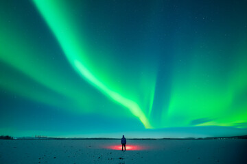 Wall Mural - tourist with red flashlight standing on snowy field against the backdrop of incredible starry sky wi