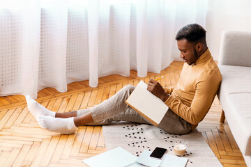 Aufkleber - Afro Student Guy Taking Notes Preparing For Lecture Or Exam Studying Sitting On Floor At Home. Selective Focus