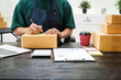 © NanSan - A man is working at his desk, preparing parcel boxes for shipment. He checks and packs items carefully, using shockproof materials, and attaches labels before sending them to customers via EMS.