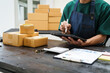 © NanSan - A man is working at his desk, preparing parcel boxes for shipment. He checks and packs items carefully, using shockproof materials, and attaches labels before sending them to customers via EMS.