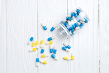 Wall Mural - Pharmacist. Many different pills and overturned bottle on white wooden table, top view