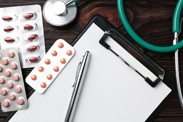 Wall Mural - Pharmacist. Many different pills, clipboard, pen and stethoscope on wooden table, top view