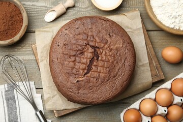 Tasty chocolate sponge cake and ingredients on wooden table, flat lay