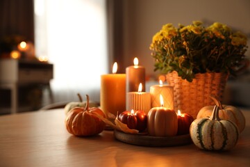 Canvas Print - Burning candles, pumpkins and flowers on wooden table indoors. Space for text