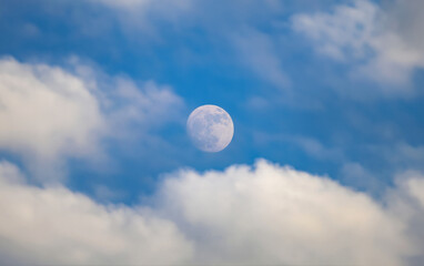 beautiful cloudscape with bright blue sky and moon in foreground, perfect for serene nature photogra