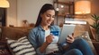 © jdis photo - Happy woman on the couch shopping online at home in the living room. Happy young woman shopping online through digital tablet using credit card at home