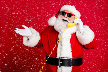 Canvas Print - Portrait of nice handsome cheerful cheery bearded Santa father answering calls discussing event consultation service call center operator isolated bright vivid shine vibrant red color background