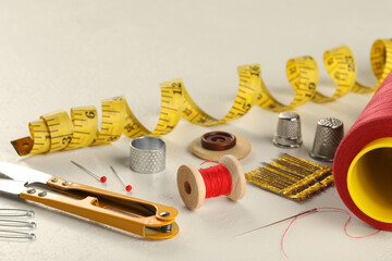 Sticker - Different sewing tools on white textured table, closeup