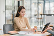 © kenchiro168 - young woman is engaged in discussion at modern workspace, showcasing thoughtful expression while seated at wooden table with notebooks and coffee cup.