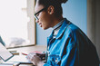 © BullRun - Side view of positive female student using public internet for making shopping on web store during break from exam preparation, dark skinned skilled woman searching information for course work
