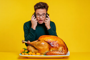 Wall Mural - Portrait of elegant young man speak telephone roasted thanksgiving day turkey isolated on yellow color background