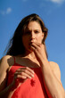 © Connect Images - Woman in a red dress under a blue sky looking contemplatively into the distance.