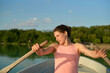 © Connect Images - A woman rows a boat on a tranquil lake surrounded by greenery during sunset.