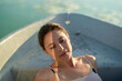 © Connect Images - Woman relaxing in a boat with gentle sunlight on her face.