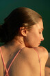 © Connect Images - Side profile of a young woman with wet skin against a green background.