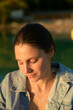 © Connect Images - Young woman enjoying a moment of tranquility in golden hour sunlight.
