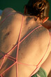 © Connect Images - Close-up of a woman's sun-kissed back with wet sand particles adhering to her skin, and her wearing a pink crisscross strapped swimsuit.