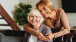 © InsideCreativeHouse - Happy daughter embracing from behind elderly mother at living room