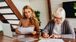 © InsideCreativeHouse - Senior woman with help of her daughter making bills at home