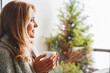 © InsideCreativeHouse - Thoughtful middle aged woman enjoying her coffee under blanket at home and looking in the window
