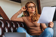 © InsideCreativeHouse - Home office. Confident business woman working with laptop and papers in living room