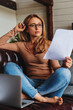 © InsideCreativeHouse - Vertical shot of business woman working with laptop and papers in living room