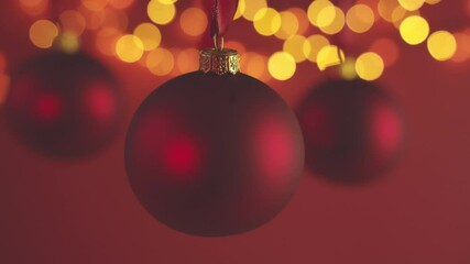 Wall Mural - christmas baubles hanging against red background and defocused lights. christmas decoration.