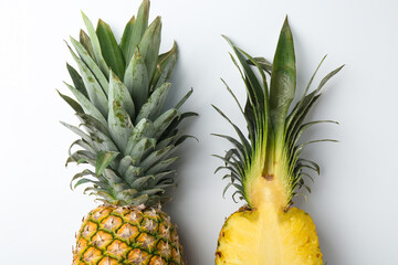 Whole and cut ripe pineapples on white background, flat lay