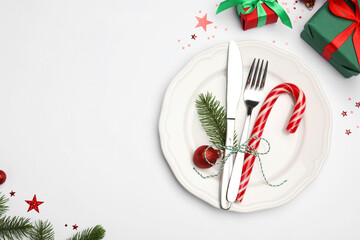 Canvas Print - Christmas table setting with plate, cutlery and festive decor on white background, flat lay. Space for text