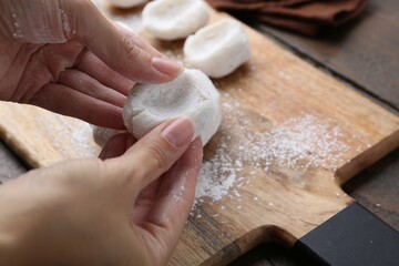 Sticker - Woman making tasty mochi at wooden table, closeup