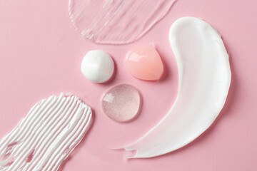 smears of different cosmetic products on pink background, flat lay