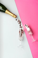 Sticker - Glasses with confetti and bottle of sparkling wine on pink background, flat lay. Christmas decor