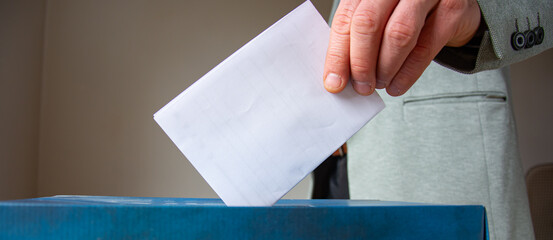 Man putting his vote into ballot box on light grey background  closeup. Space for text