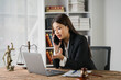 © Kritdanai - Lawyer on a Critical Call: Focused Female Attorney on phone, laptop, and legal documents.  Serious expression, conveying urgency and importance of legal matters.
