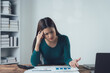 © Kritdanai - The Pressure is On: A woman struggles to comprehend a complex financial report, her furrowed brow and hand on her forehead revealing the stress and pressure of the situation.