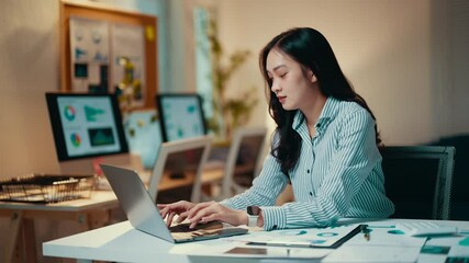 Poster - Businesswoman is sitting at her desk in her office, working on a laptop. She is typing on the keyboard and looking at the screen