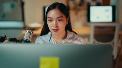 Aufkleber - Young asian woman working late in a home office, focusing intently on her tasks. A determined expression reflects her ambition and commitment to achieving success in her career