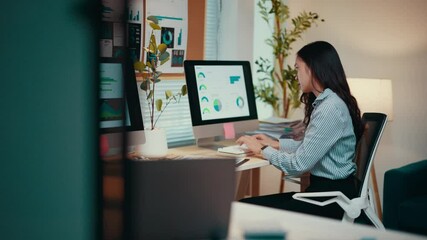 Poster - Asian businesswoman sits at her desk, working on a computer. Analyzing data and managing spreadsheets, she demonstrates professionalism in a corporate environment