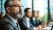 © BoOm - Serious businessman in a meeting with colleagues, focused on discussion.